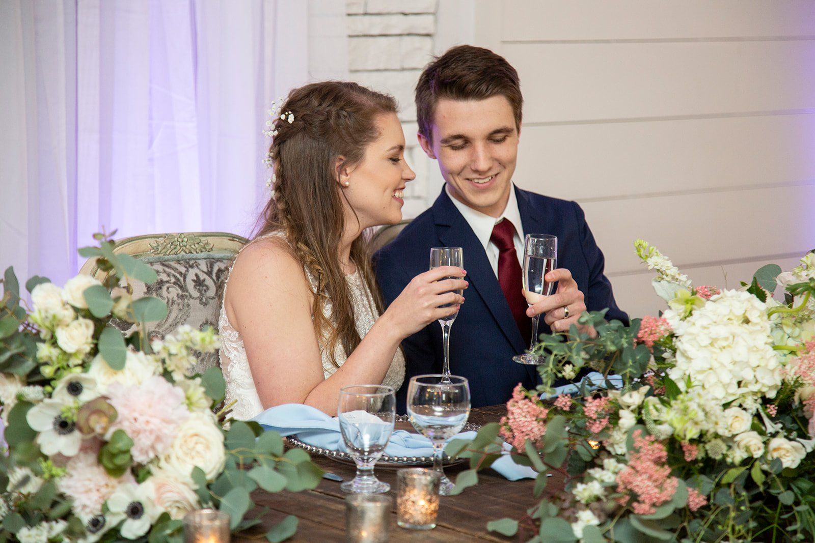 A bride and groom are toasting with champagne at their wedding reception.