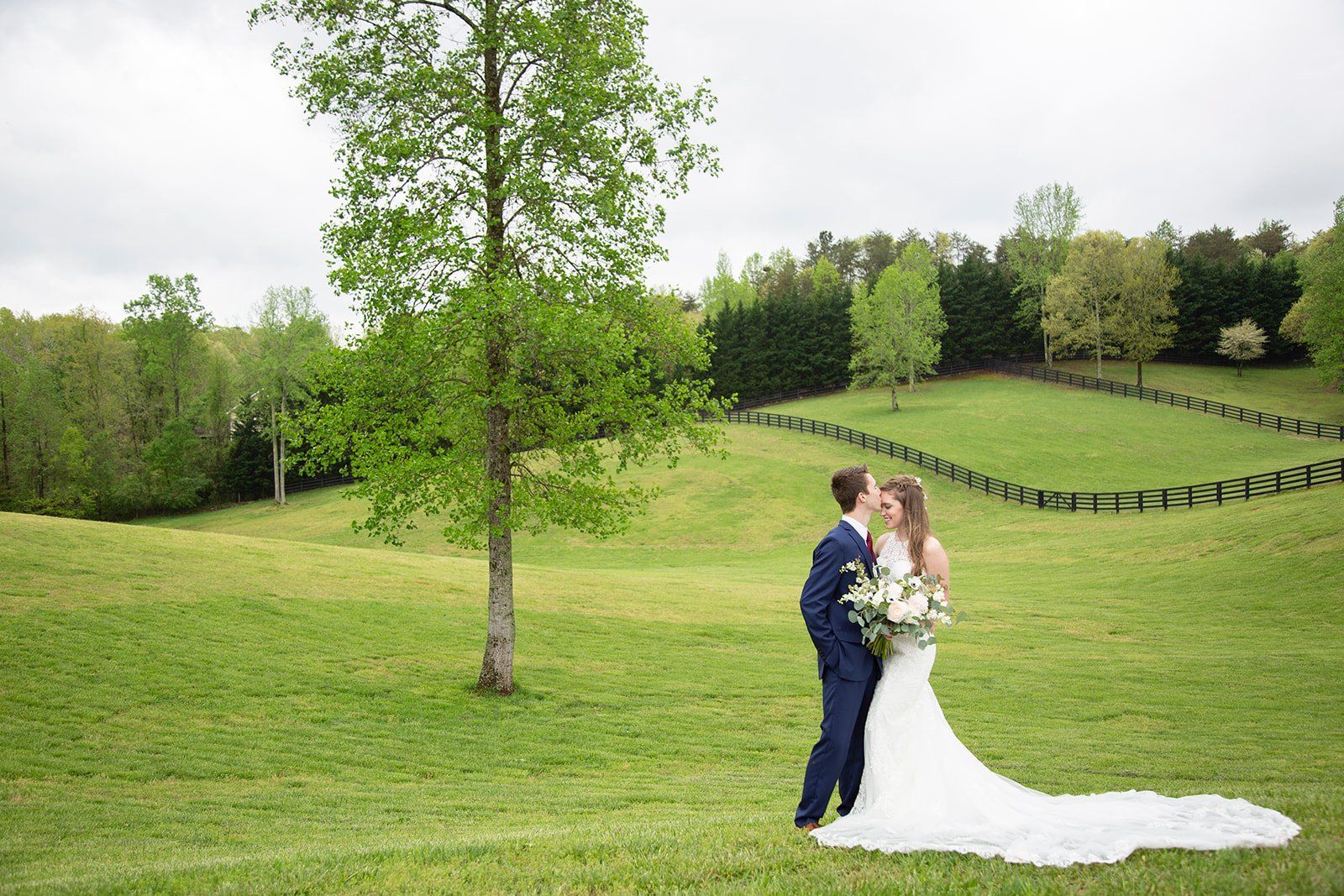 A bride and groom are standing in a grassy field.
