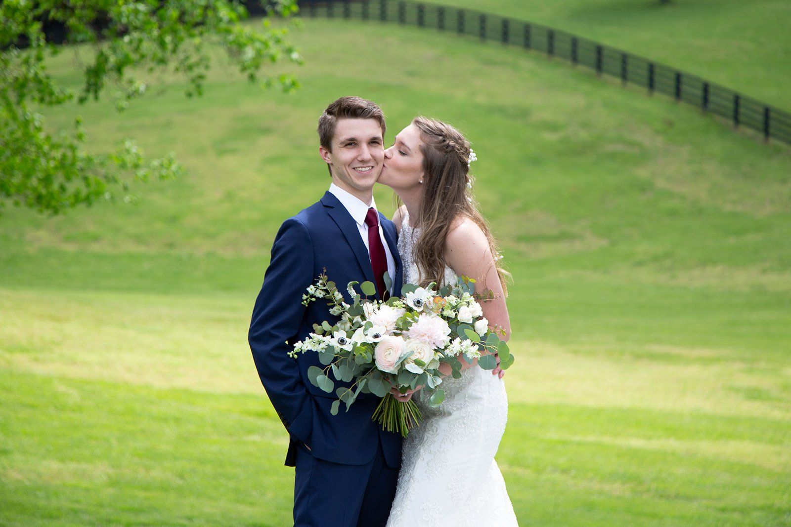 A bride and groom are kissing in a field.