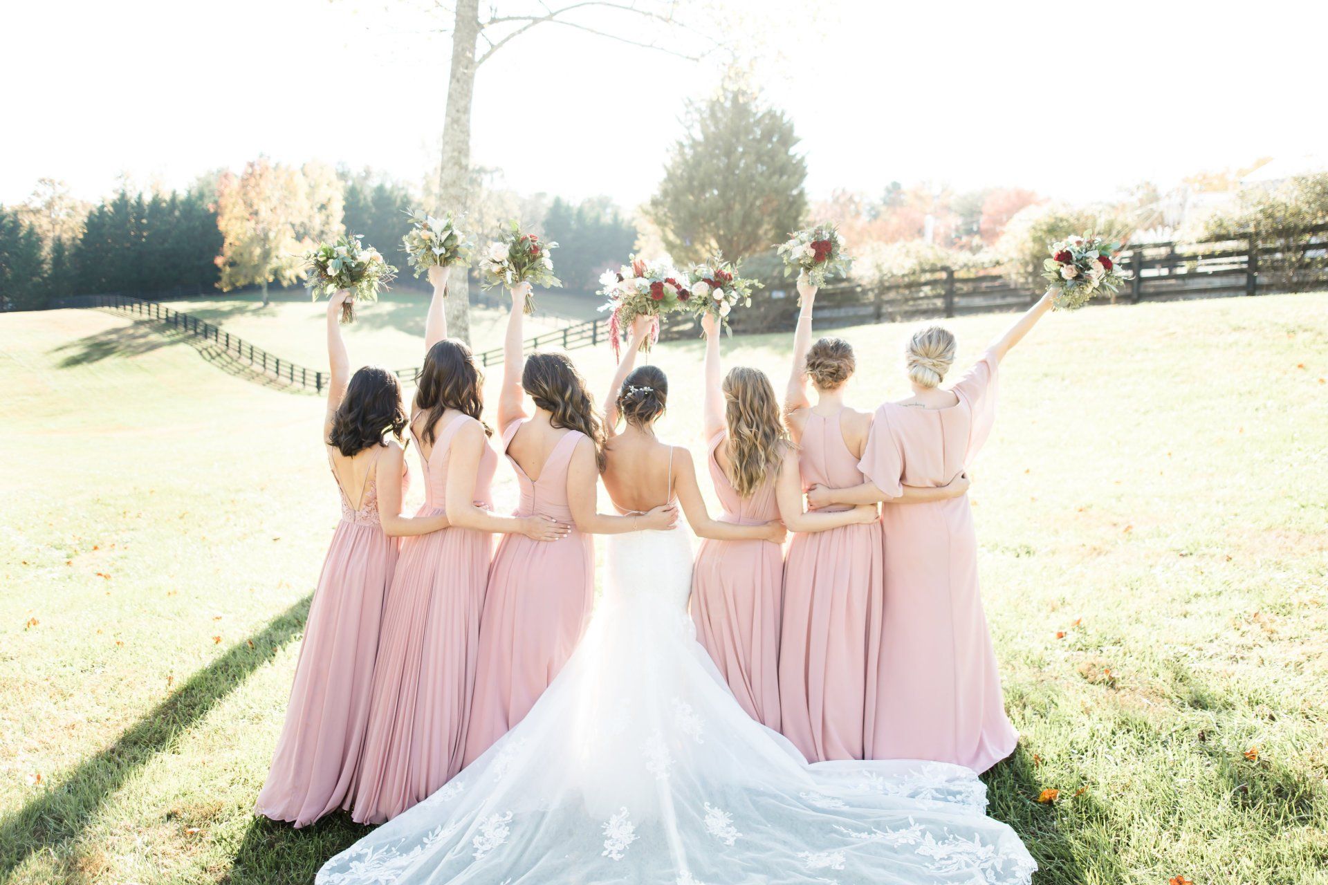 A bride and her bridesmaids are posing for a picture in a field.