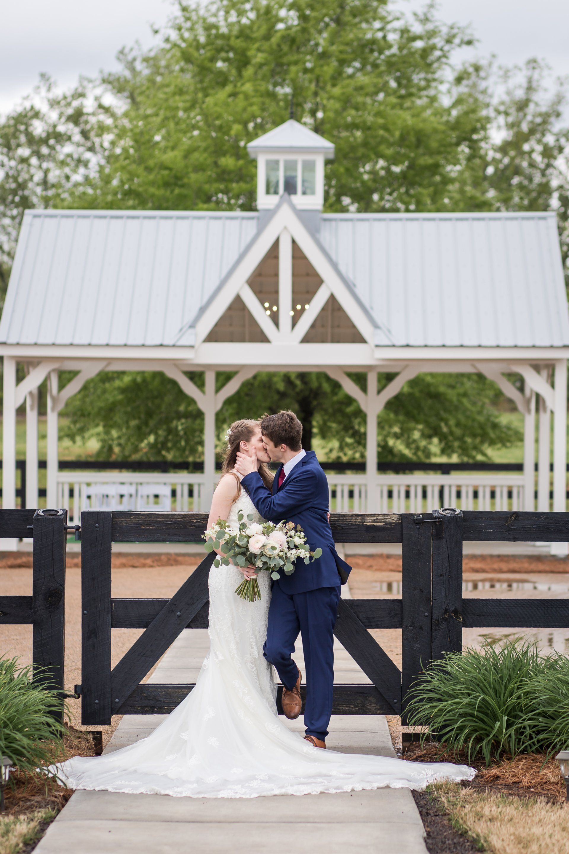 A bride and groom are kissing in front of a gazebo.