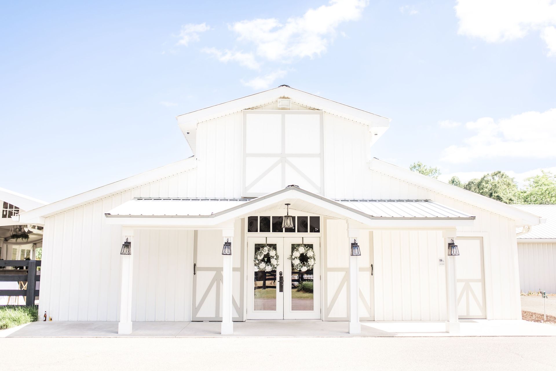 A white barn with a porch and a blue sky in the background.