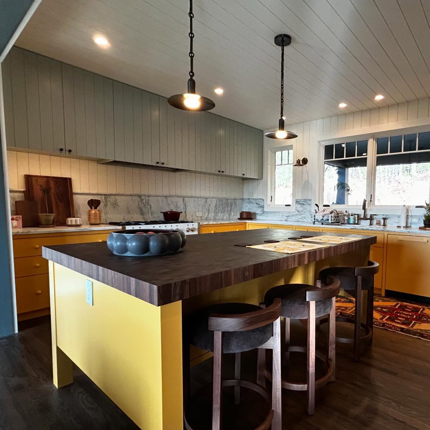 Yellow and blue kitchen with island and pendant lights.