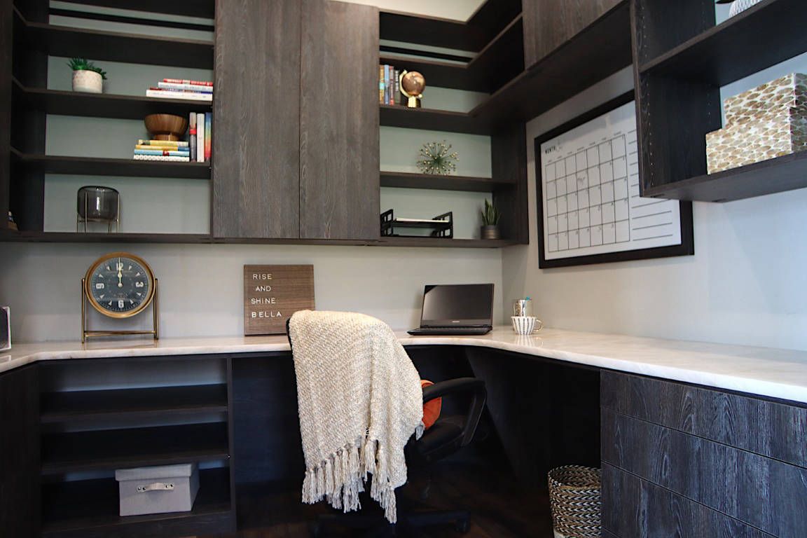 Dark wood home office with shelves, desk, laptop, chair, and decorative items.