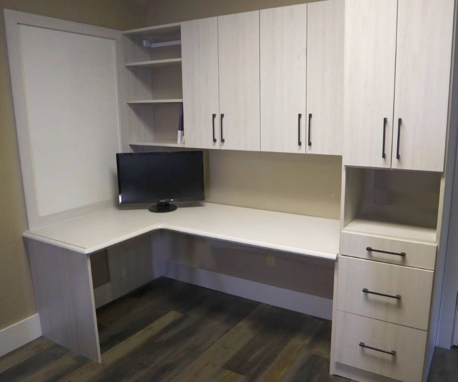 L-shaped home office desk with upper cabinets, shelves, and a tall storage cabinet. Beige cabinets, dark pulls.