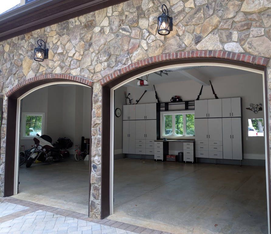 Stone garage exterior with arched doorways, interior storage, and a motorcycle.