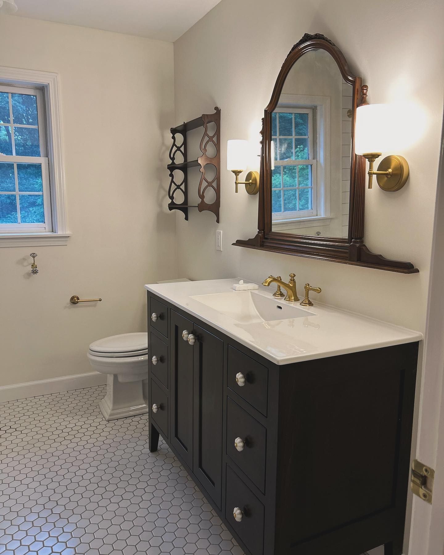 Bathroom with a dark vanity, ornate mirror, and hexagonal tile flooring.