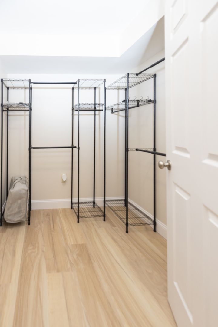 Empty walk-in closet with wire shelving and a white door. Light wood flooring and neutral walls.