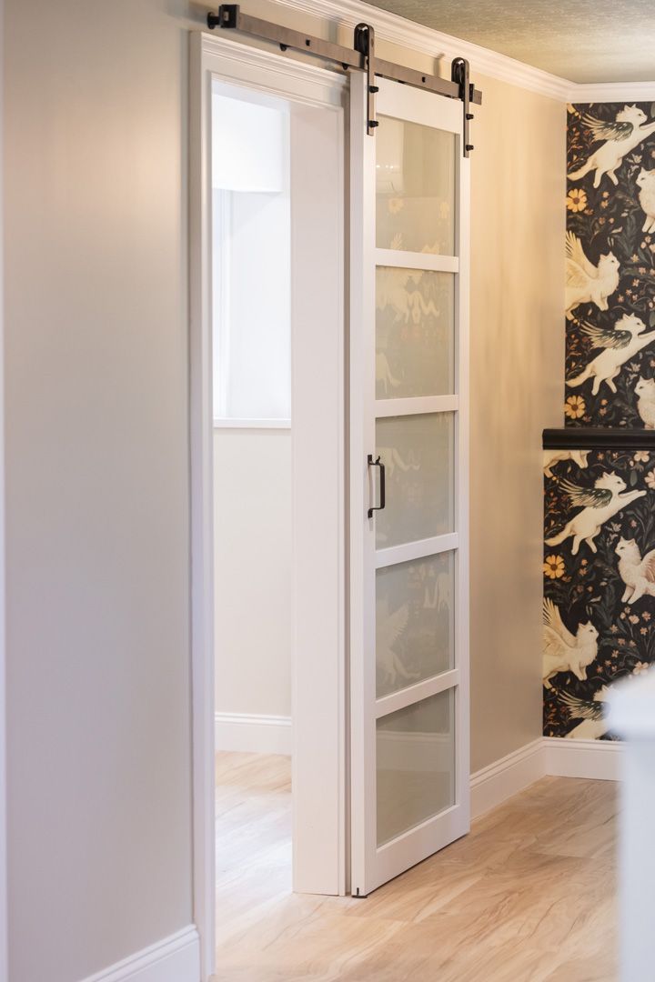 White sliding glass door on black track; open doorway into a light-filled room.