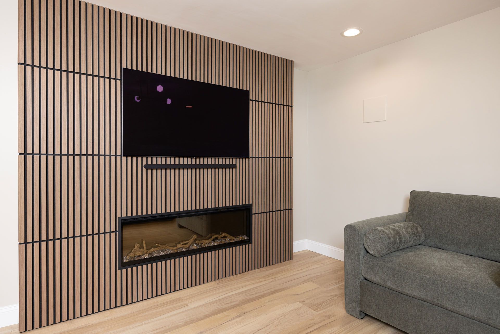 Wall with wood paneling, TV, fireplace, and sofa. Modern living room design.
