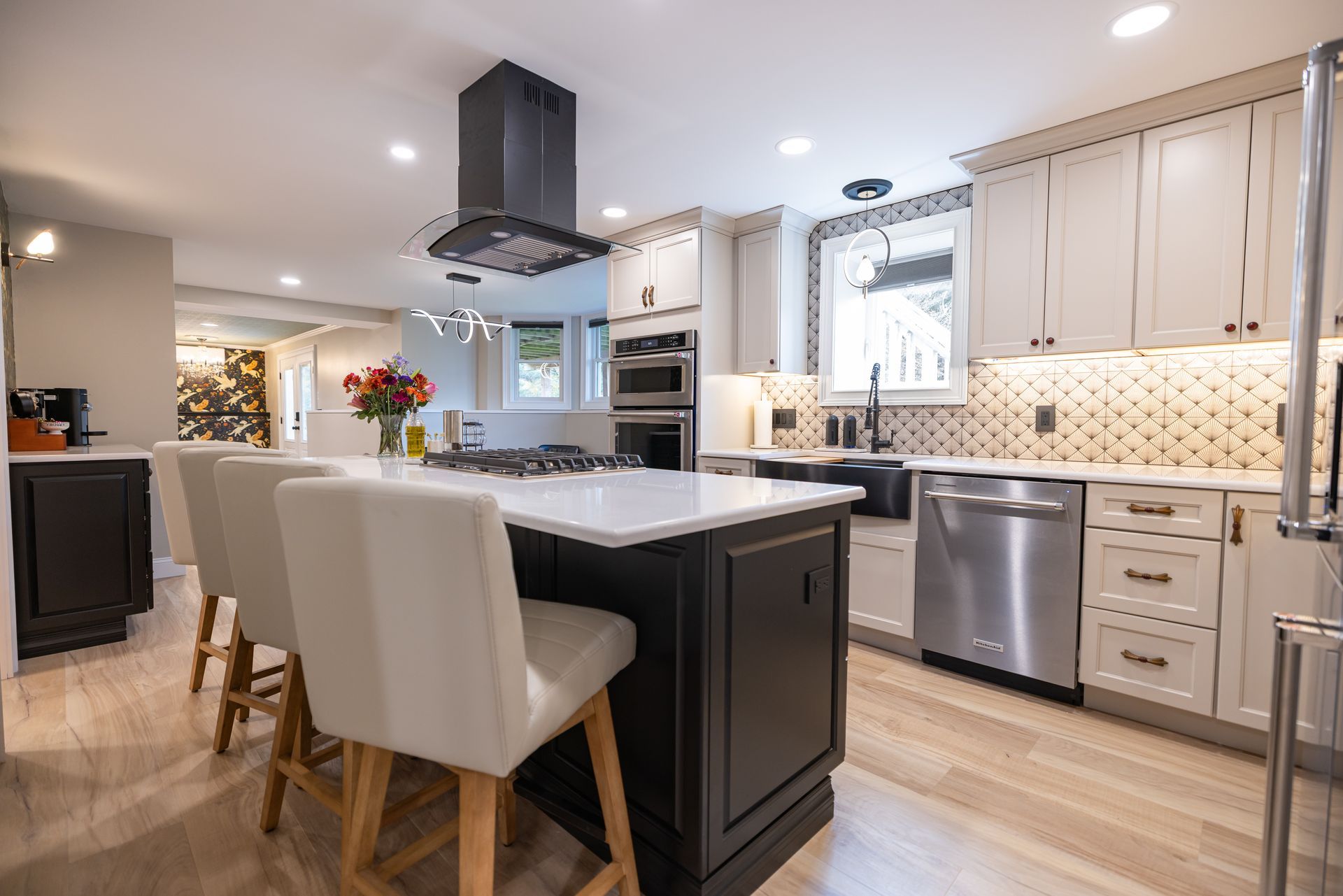 Modern kitchen with dark island, white cabinets, stainless steel appliances, and wood flooring.