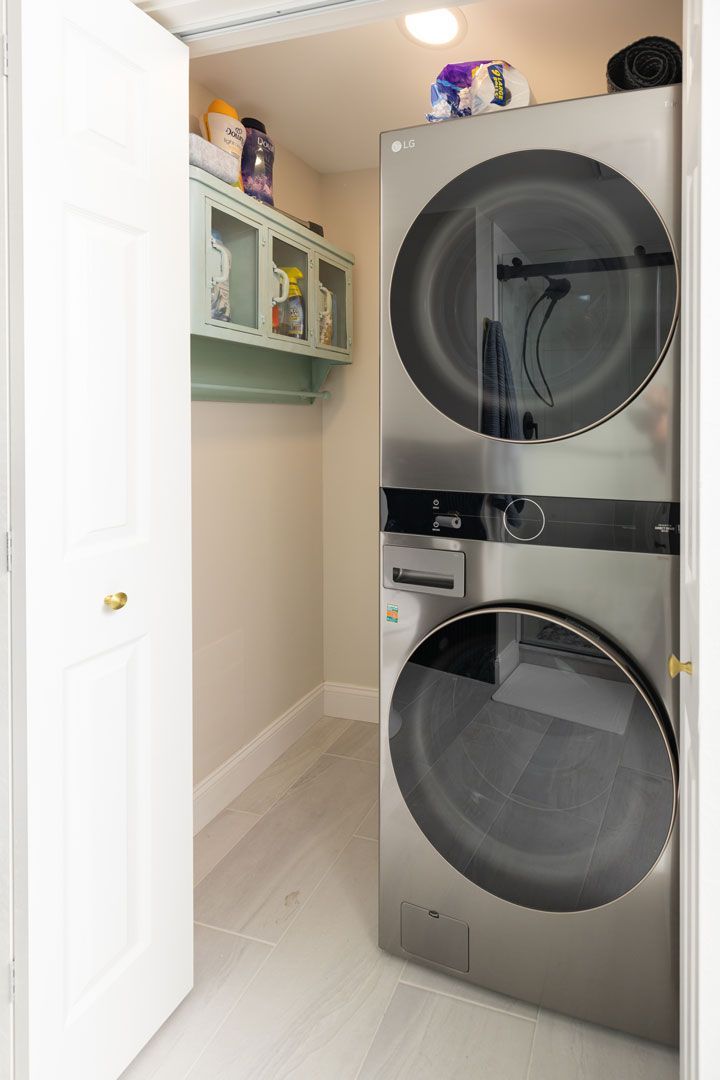 Laundry room with stacked washer and dryer, light wood floor, small storage cabinet.