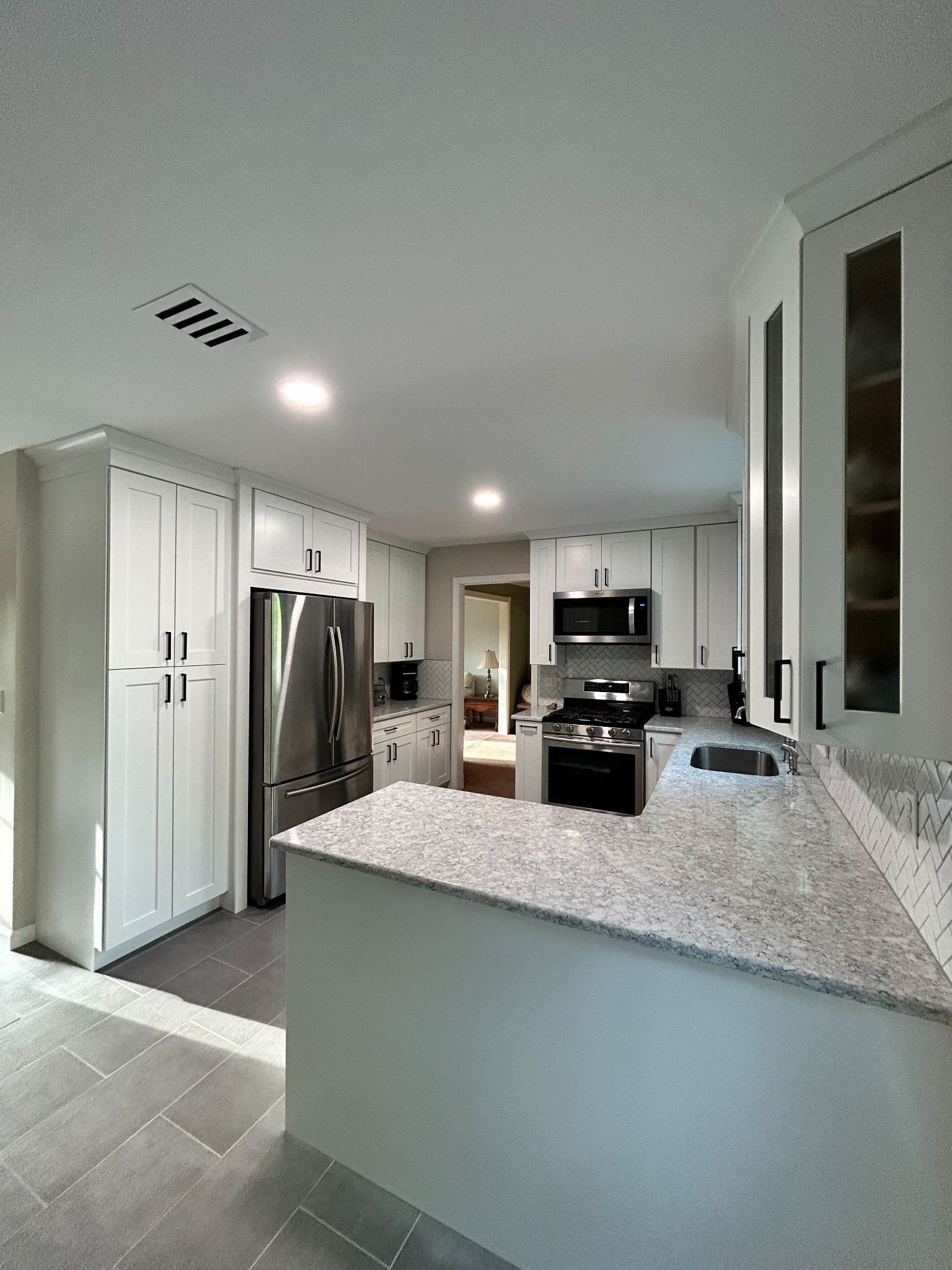 White kitchen with stainless steel appliances, light countertops, and cabinets.