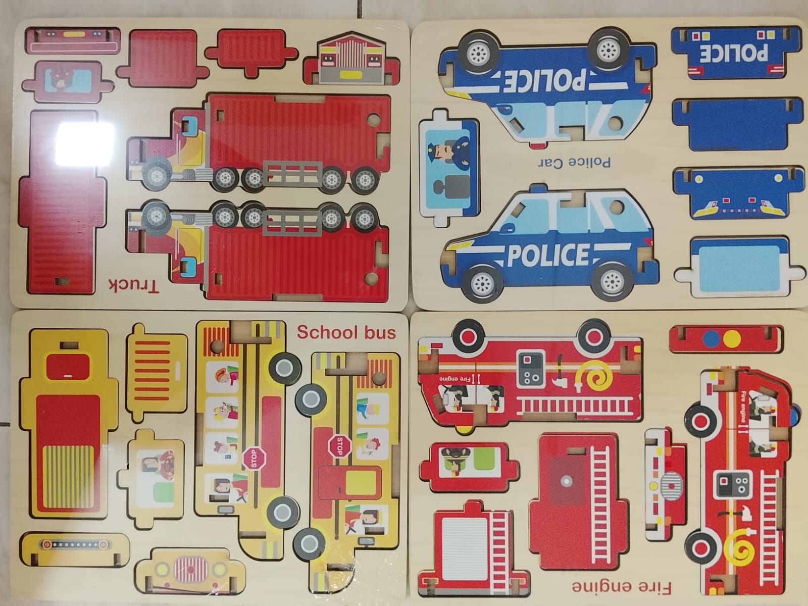Cuatro tableros de madera con imágenes de vehículos: camión, coche de policía, autobús escolar y camión de bomberos.