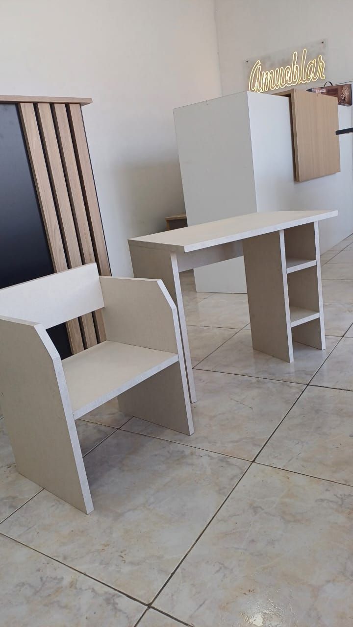 Conjunto de silla y escritorio, color beige claro, sobre un fondo de pared blanca y panel de madera.