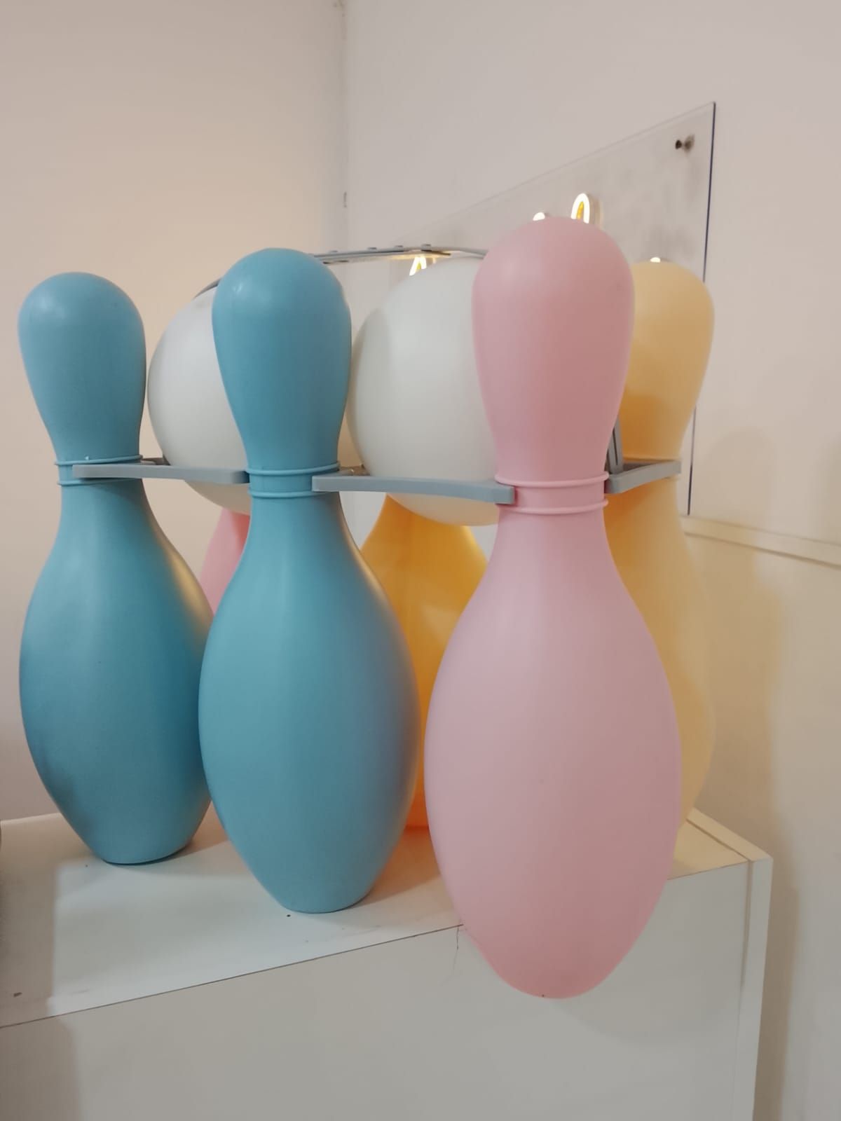 Bolos, en tonos pastel azul, rosa y amarillo, dispuestos en un estante.