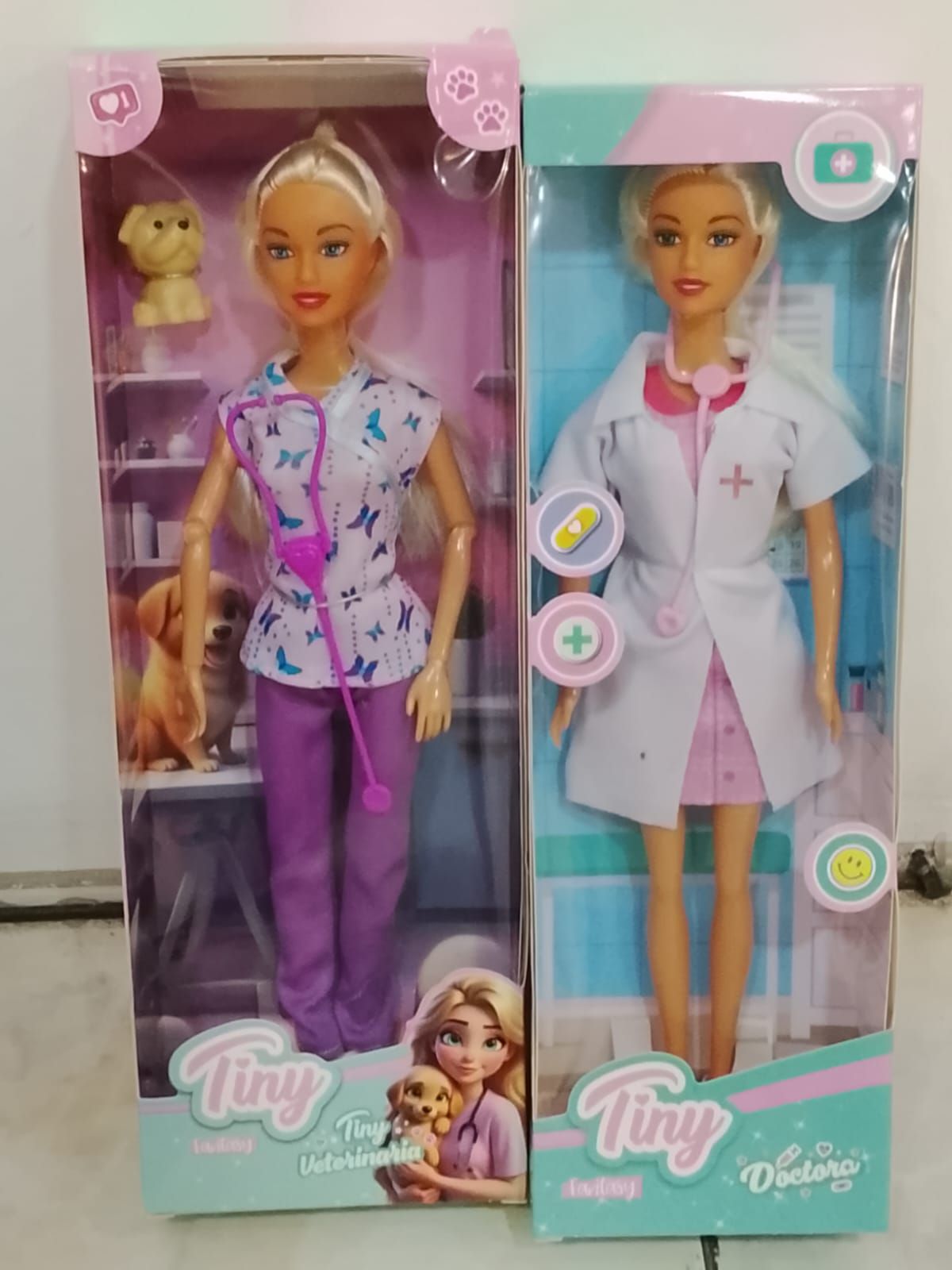 Dos muñecas en cajas: una muñeca veterinaria con animales, una muñeca doctora con bata blanca.