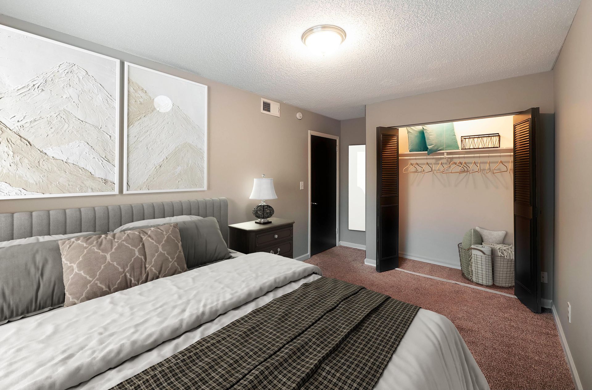 A bedroom with a bed featuring gray pillows and a patterned runner, next to a nightstand and an open closet.