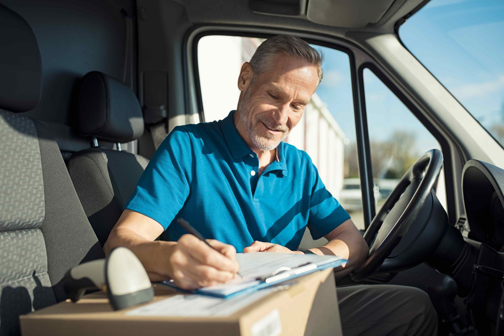 a man in a blue shirt is sitting in a van writing on a clipboard