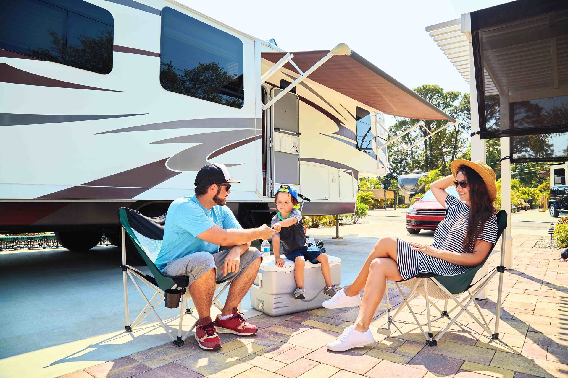 a family sits in front of a rv on a sunny day