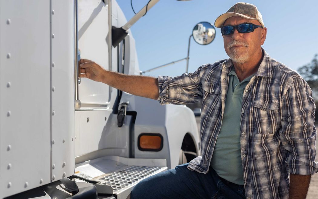a man wearing sunglasses and a hat is standing next to a truck