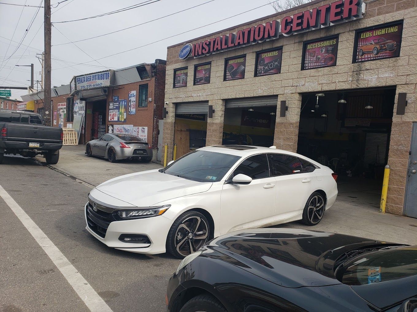 A white car is parked in front of a car dealership.