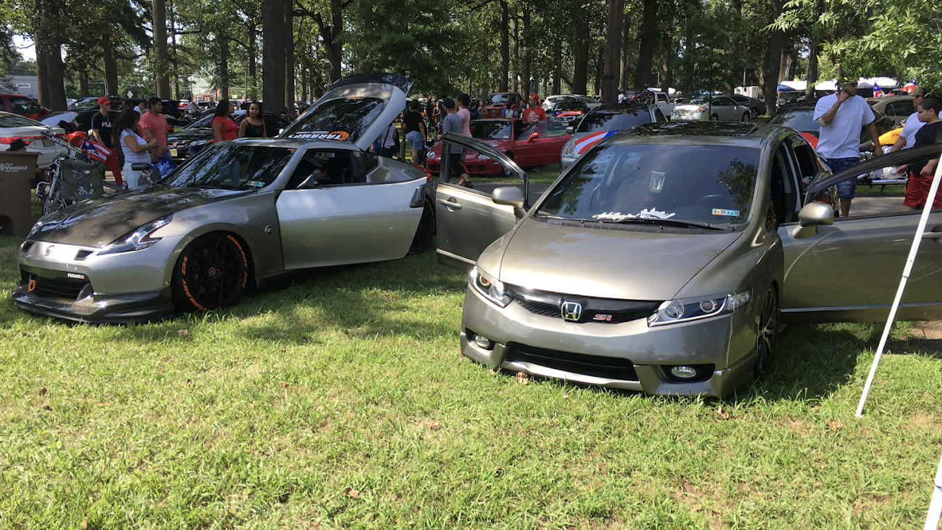 Two cars are parked in a grassy field at a car show.