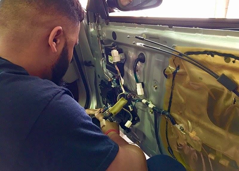 A man is working on the inside of a car door.