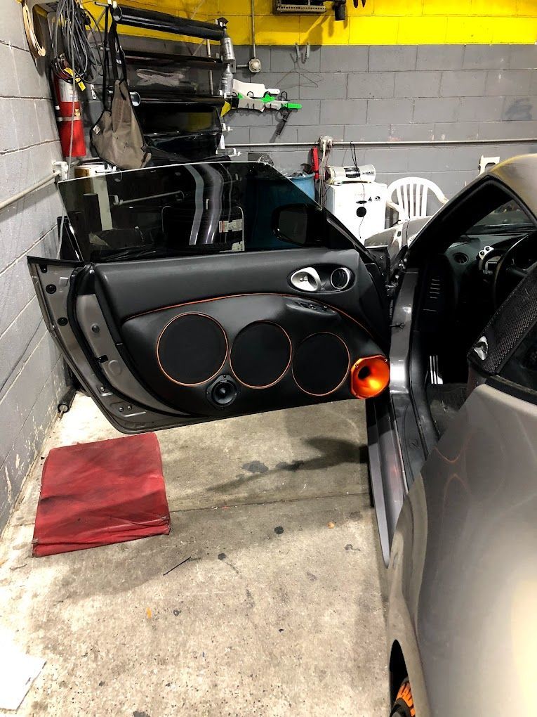 A car is sitting in a garage with its doors open.