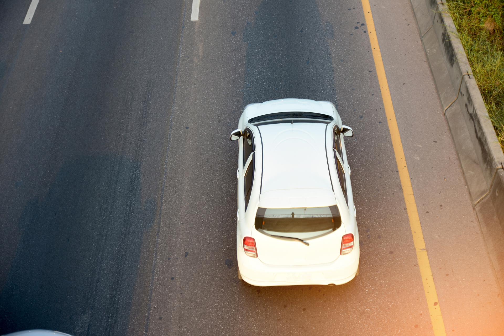 A white car is driving down a highway.