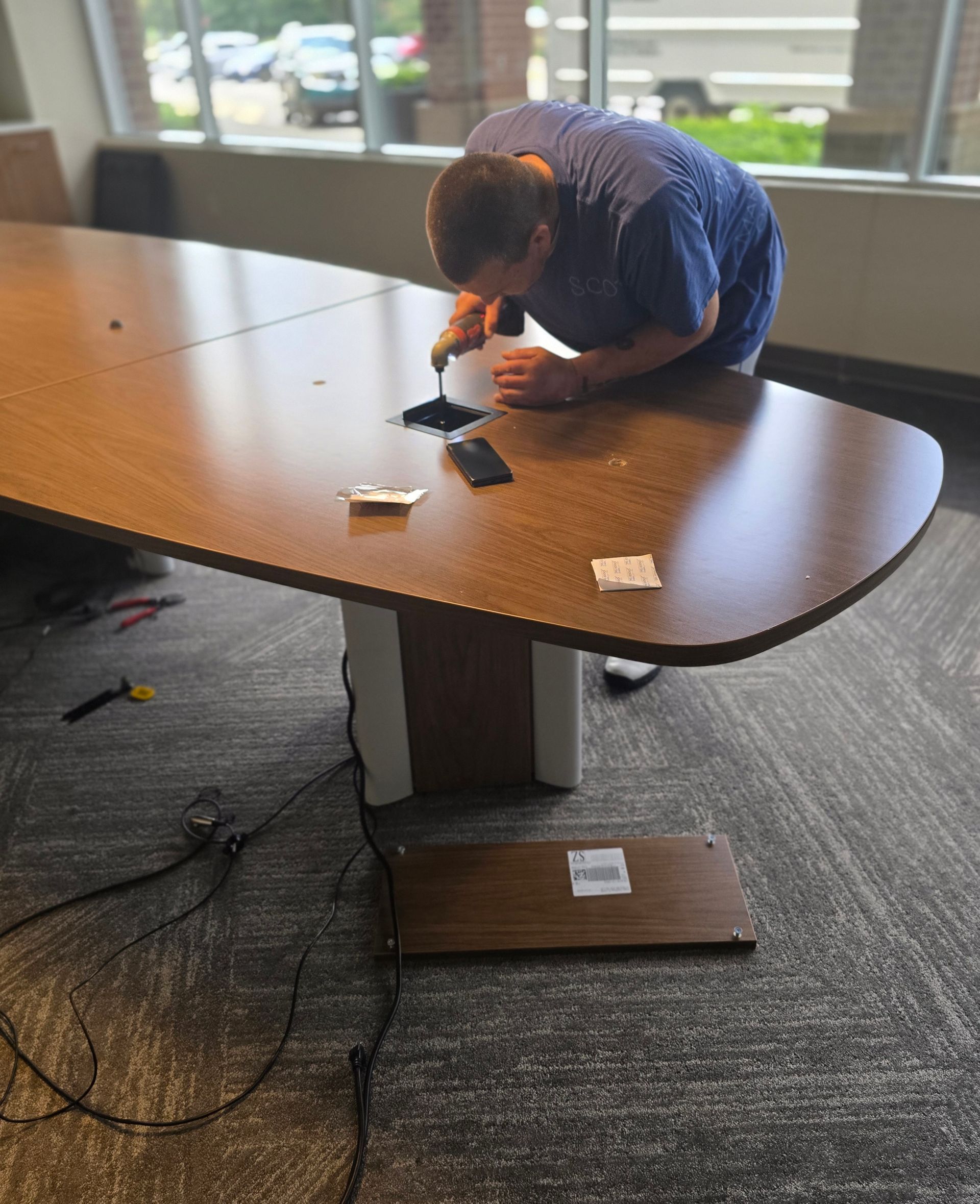 Local movers carefully disassembling a large wooden conference table for an office relocation in Cary, NC.