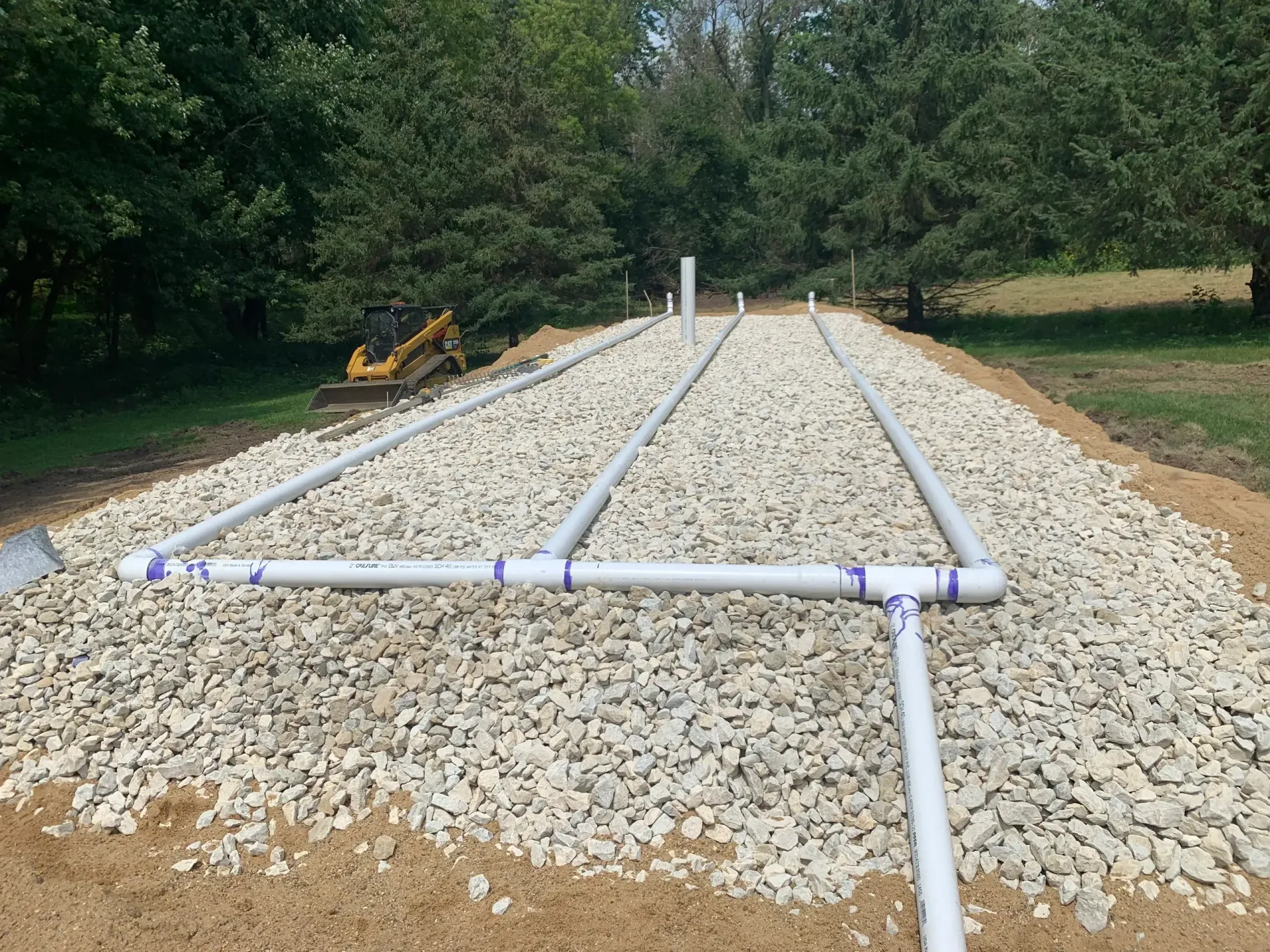 White PVC pipes laid on gravel bed for a septic system.