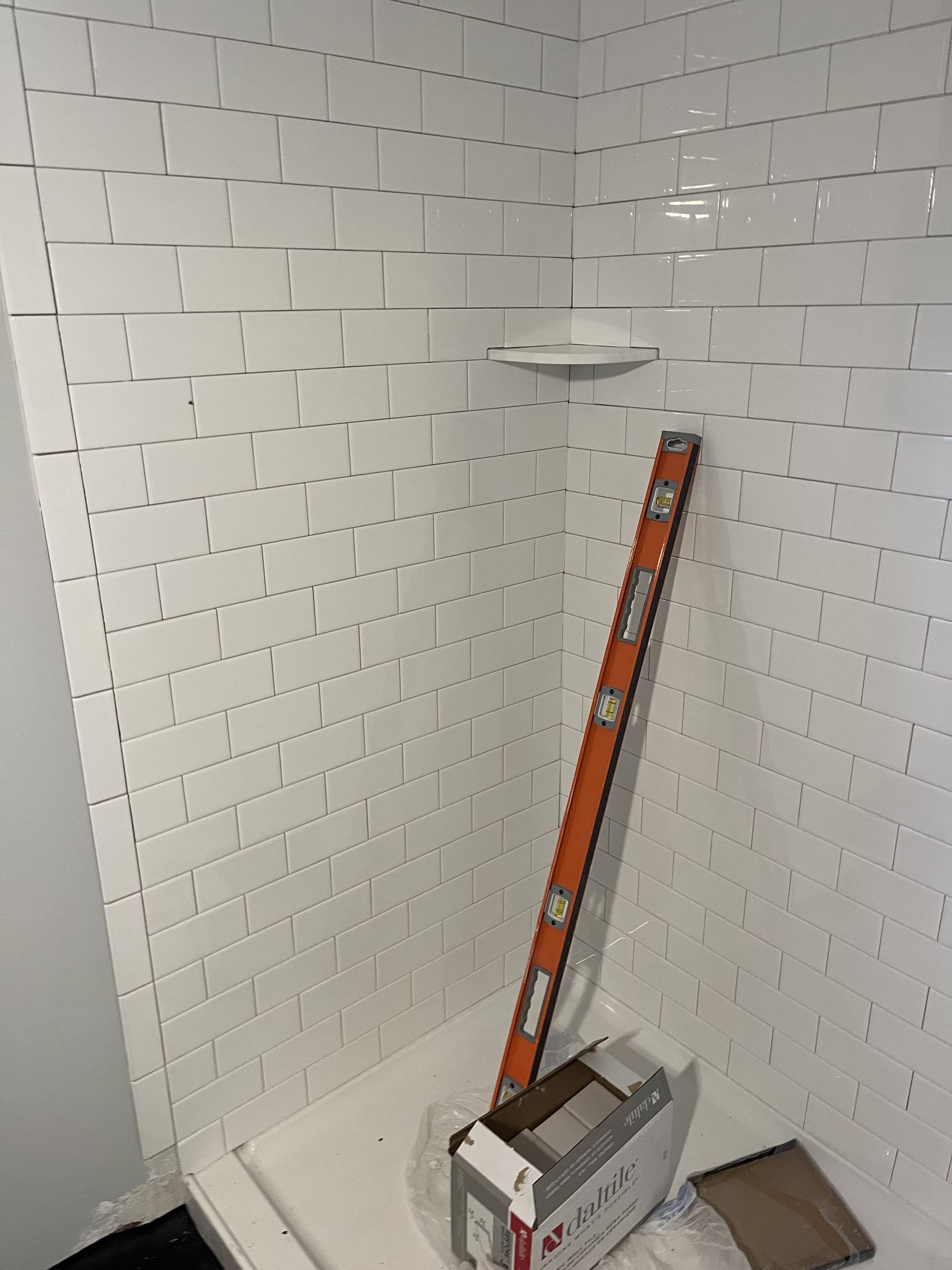 A shower with white tiles and a level in the corner.