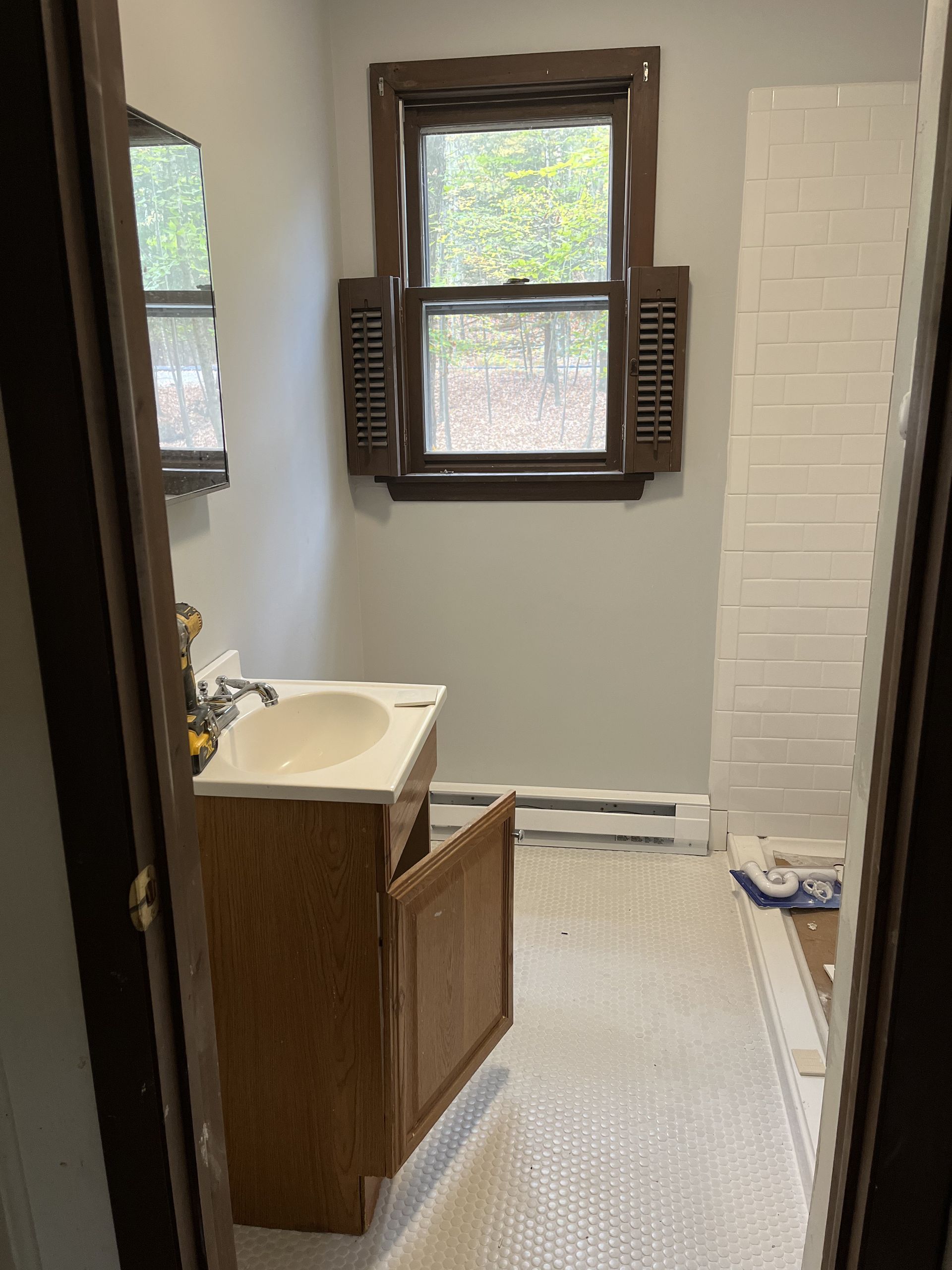 A bathroom with a sink , mirror , and shower.