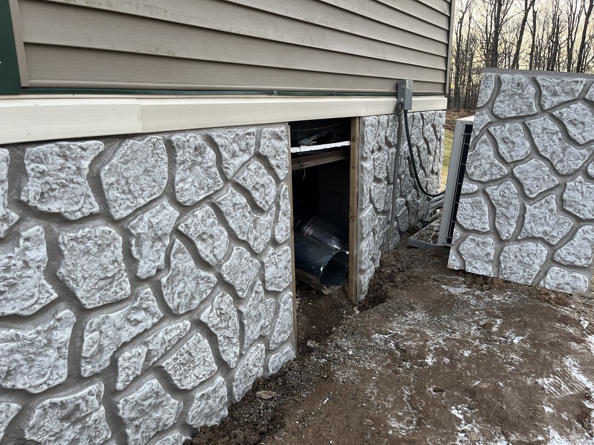 A stone wall with a hole in it next to a house.