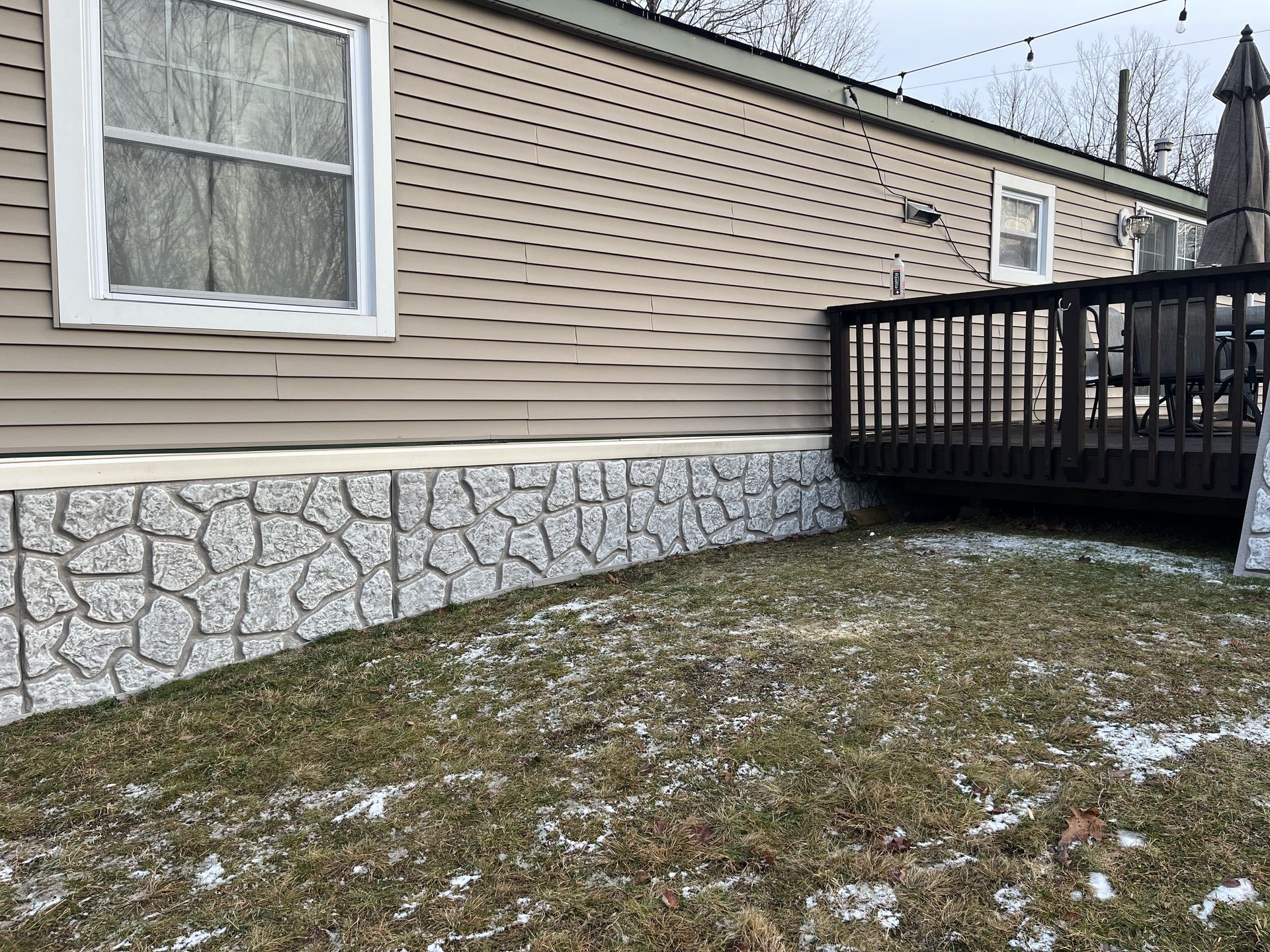A mobile home with a deck and a stone foundation.
