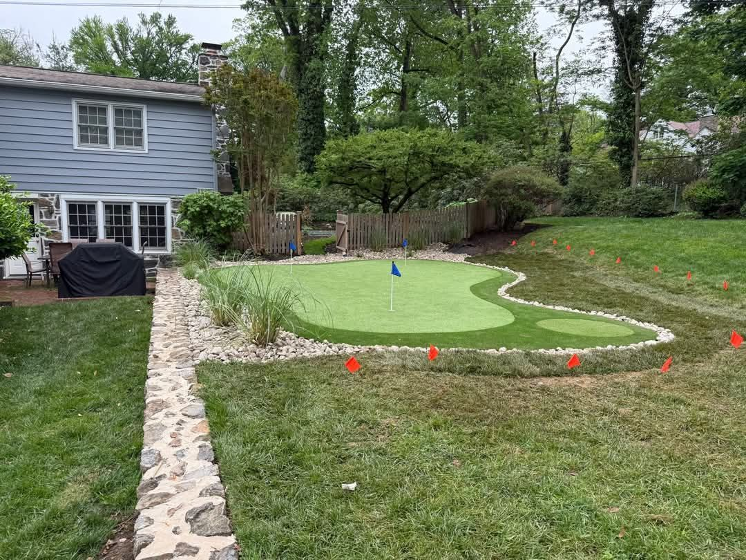 Backyard with a custom-built putting green, edged with stones. House is in the background. Newcastle