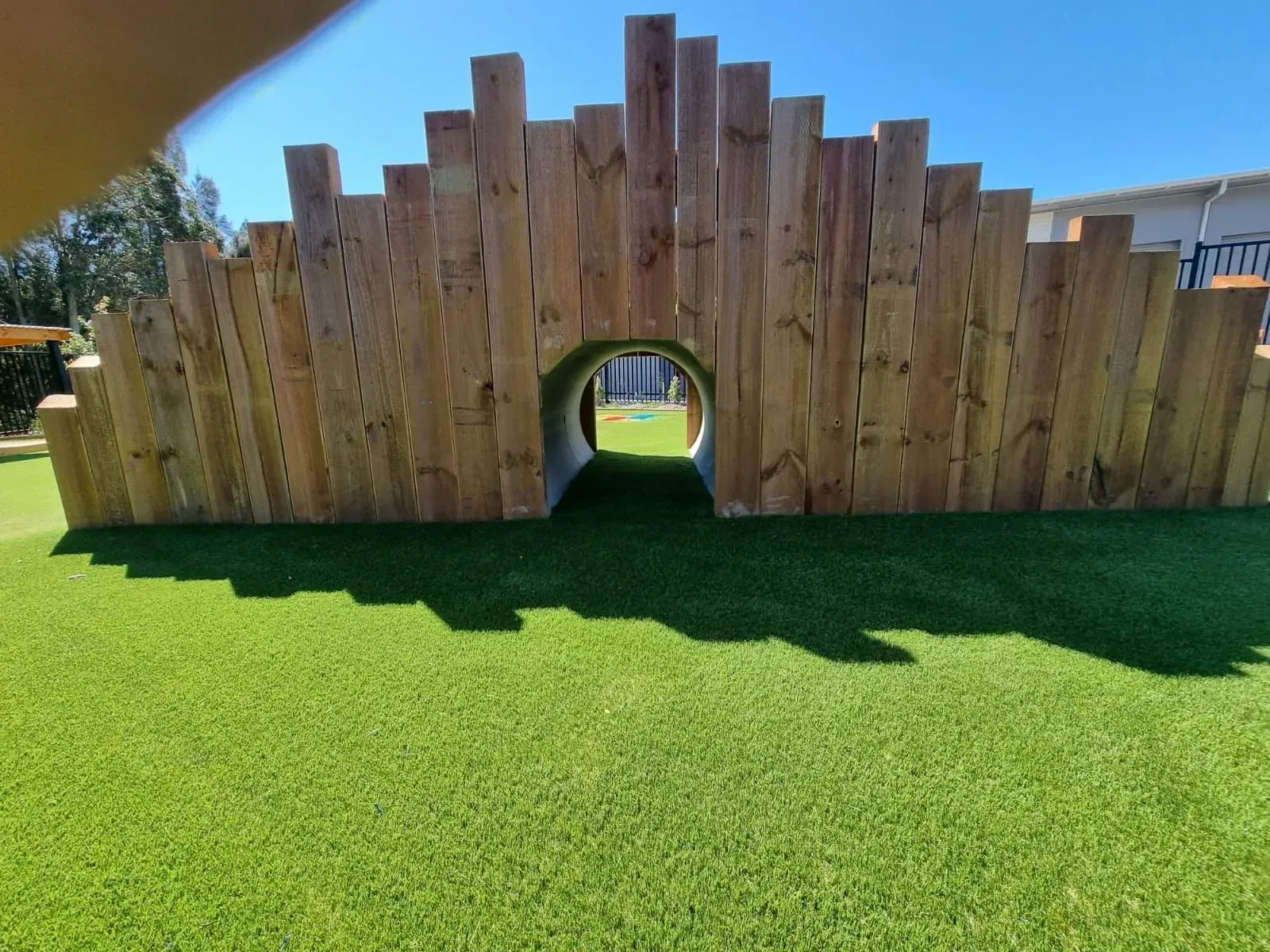 Wooden tunnel structure on green turf.
