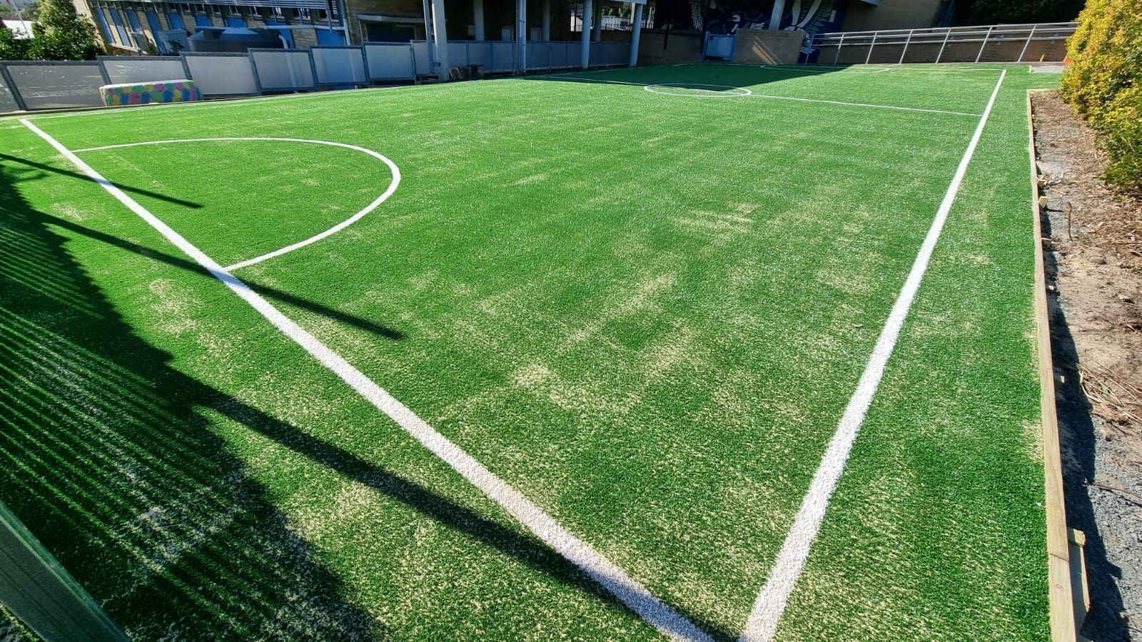 Green artificial turf soccer field with white lines.