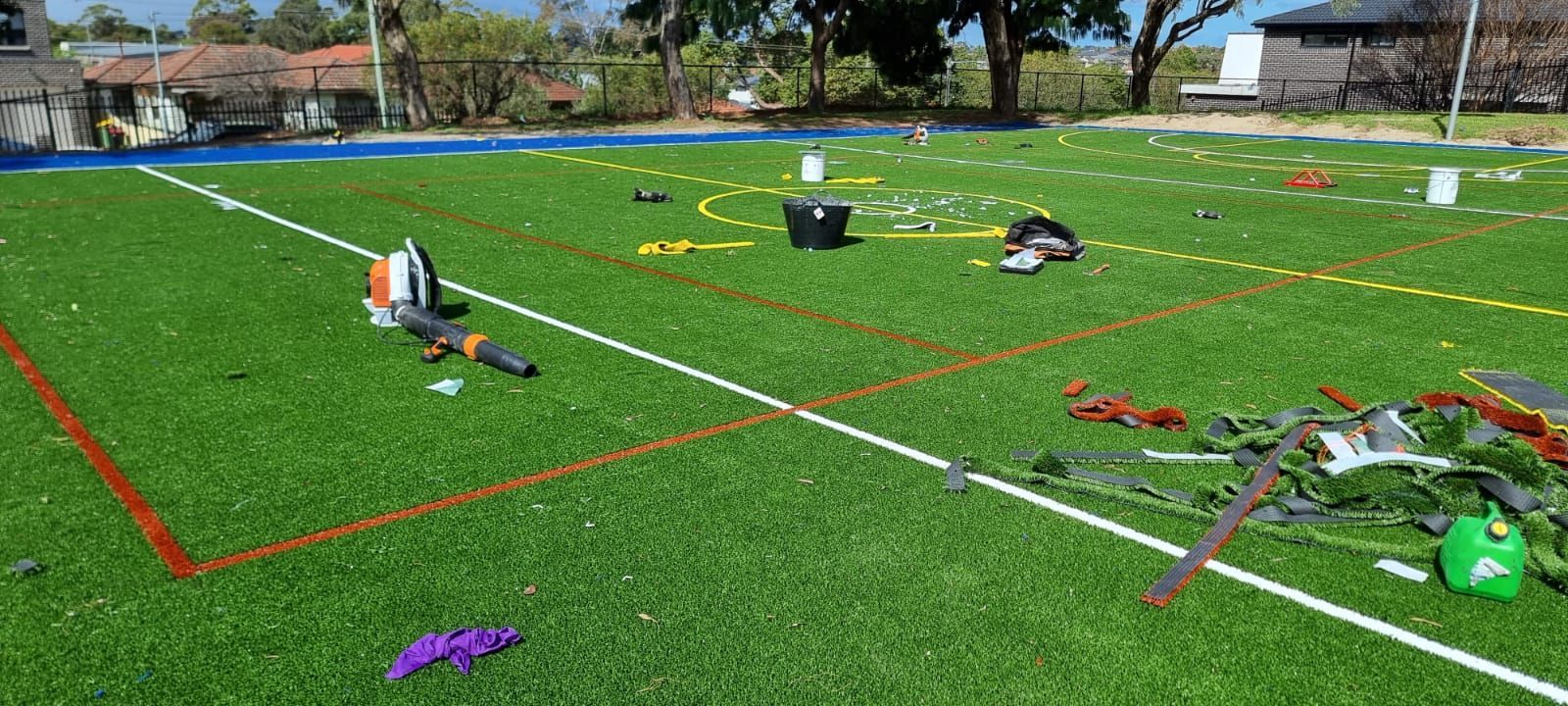 A green turf field scattered with sports equipment and debris, possibly after an event.