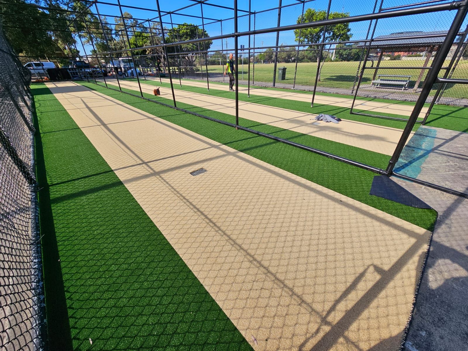Cricket practice nets on green grass field.