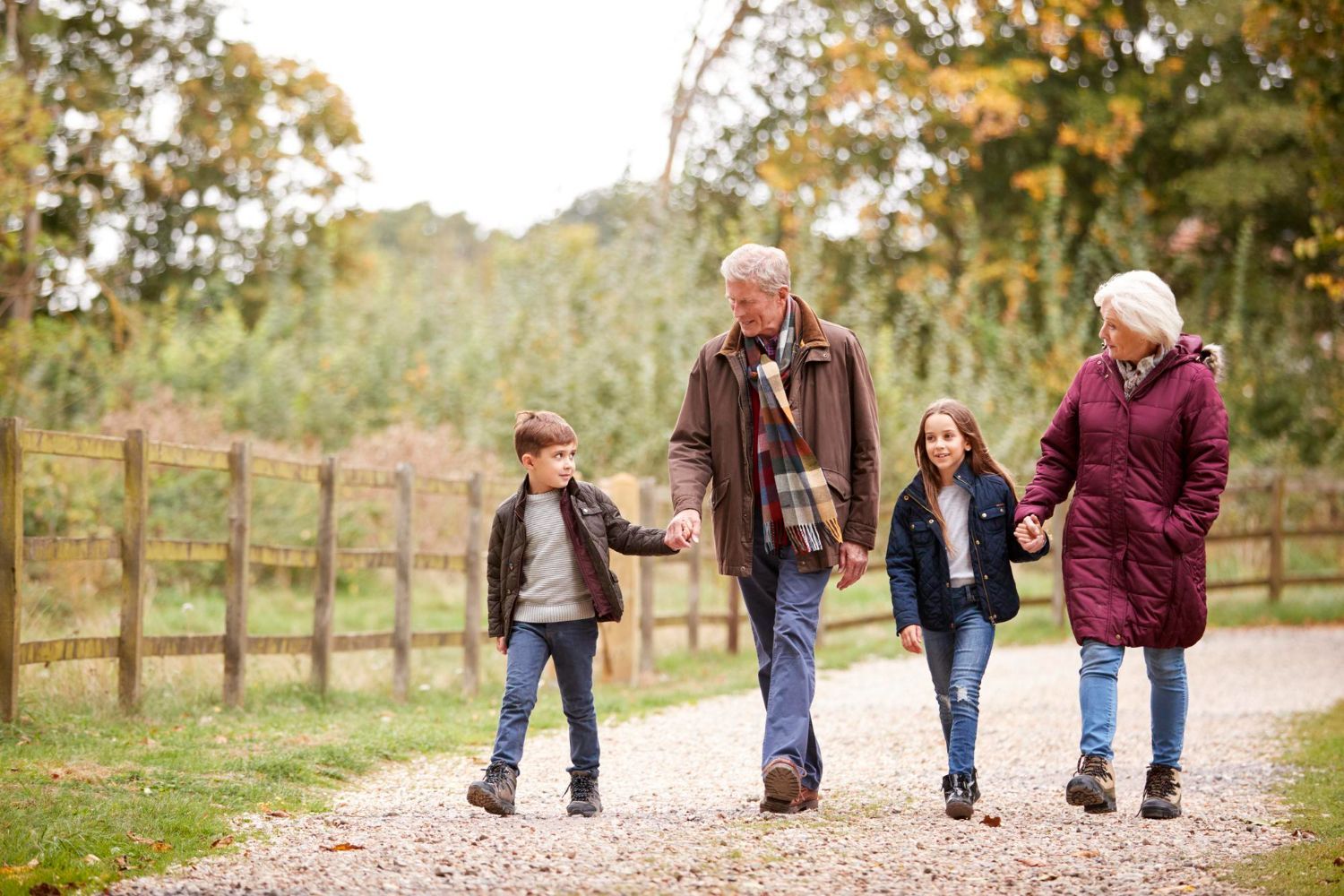 A family is walking down a dirt road holding hands.