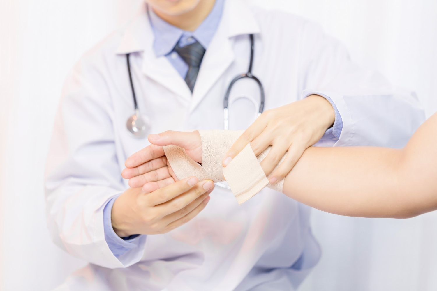 A doctor is bandaging a patient 's wrist.