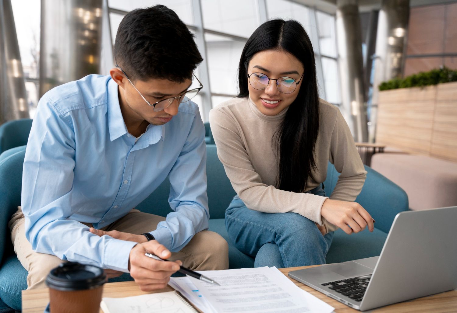 A man and a woman are sitting on a couch looking at a laptop.