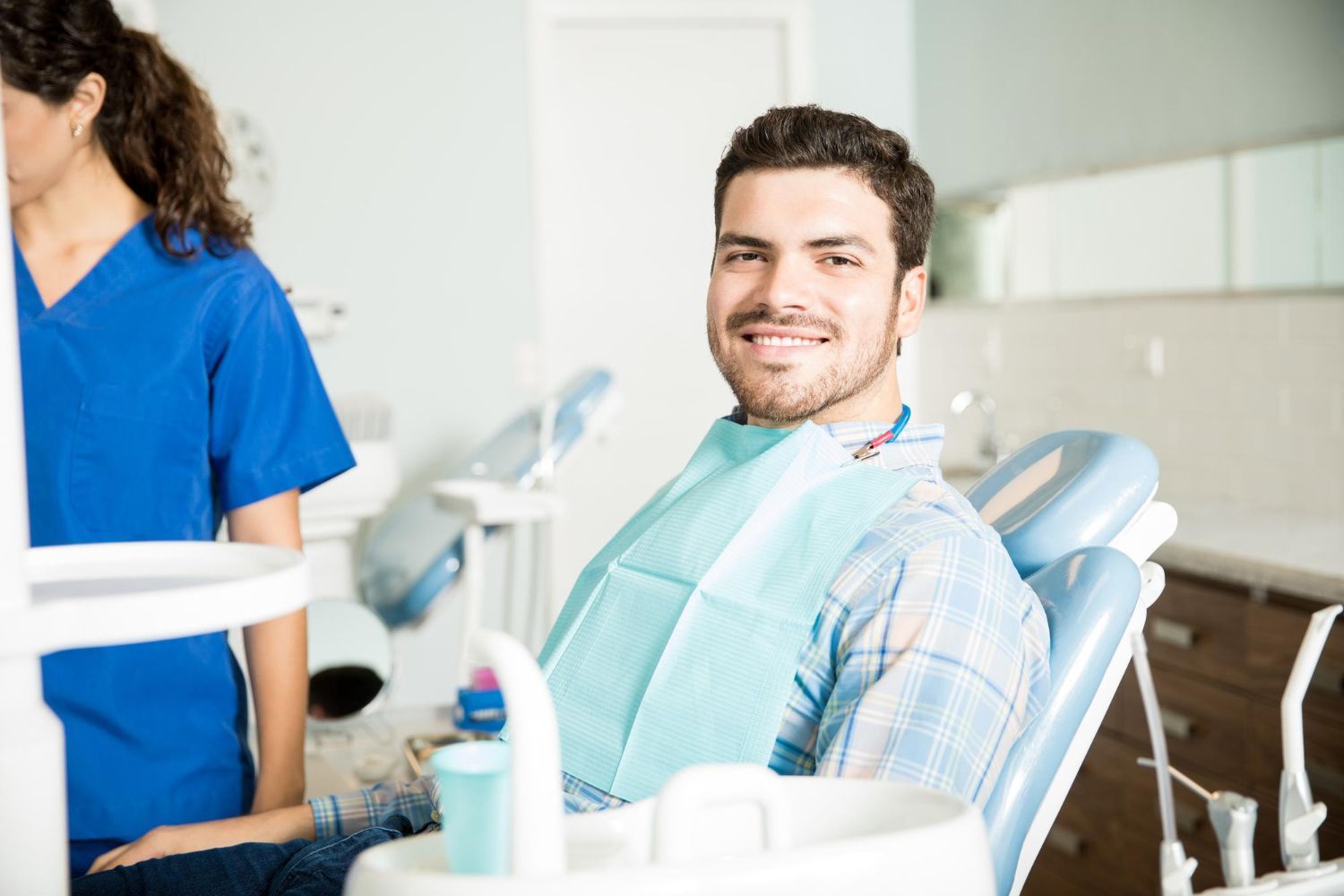 A man is sitting in a dental chair and smiling at the camera.