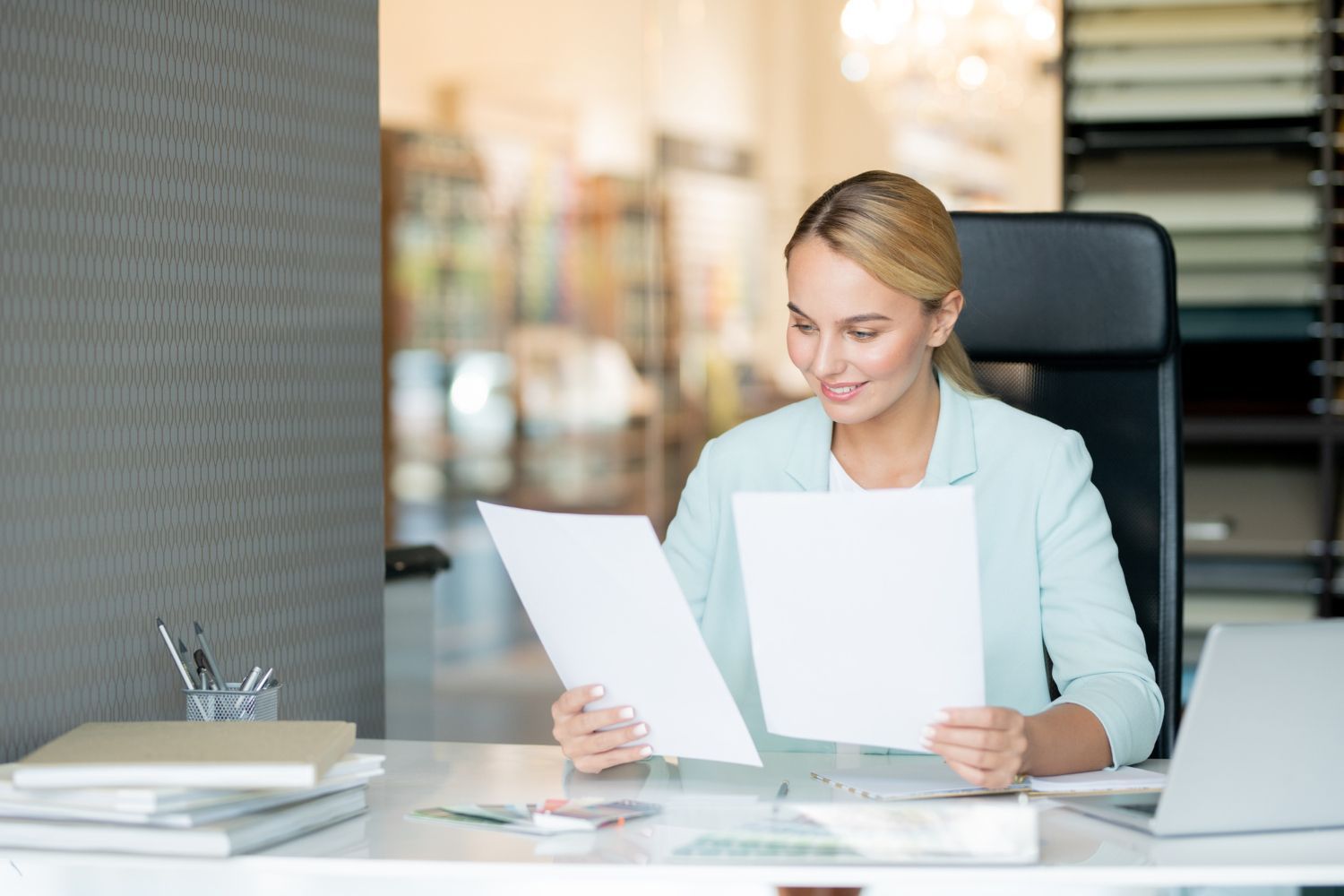 A woman is sitting at a desk looking at a piece of paper.
