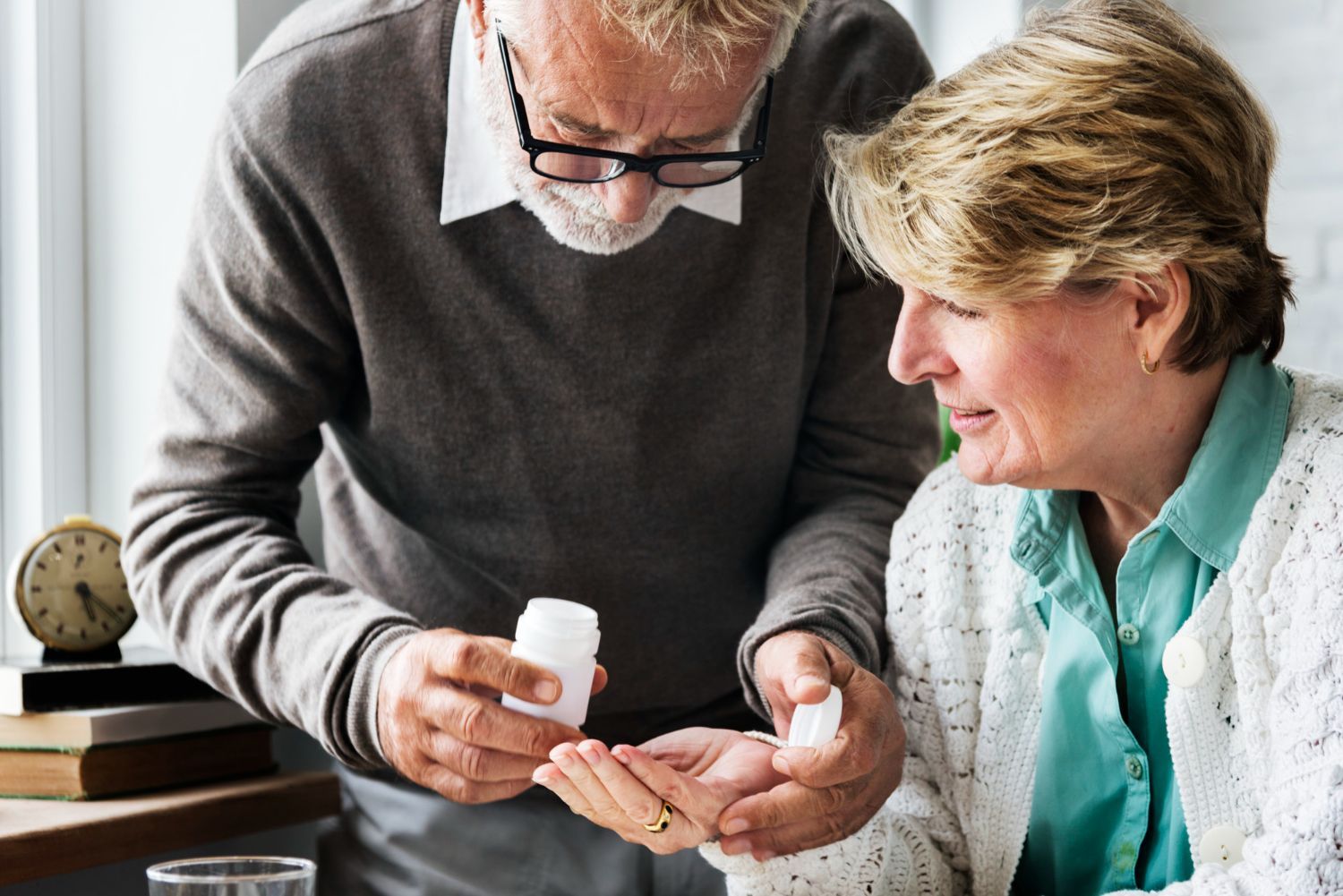 A man is giving a woman a bottle of pills.