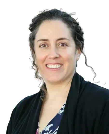 A smiling person with dark, wavy hair, wearing a black cardigan over a blue patterned top against a white background.