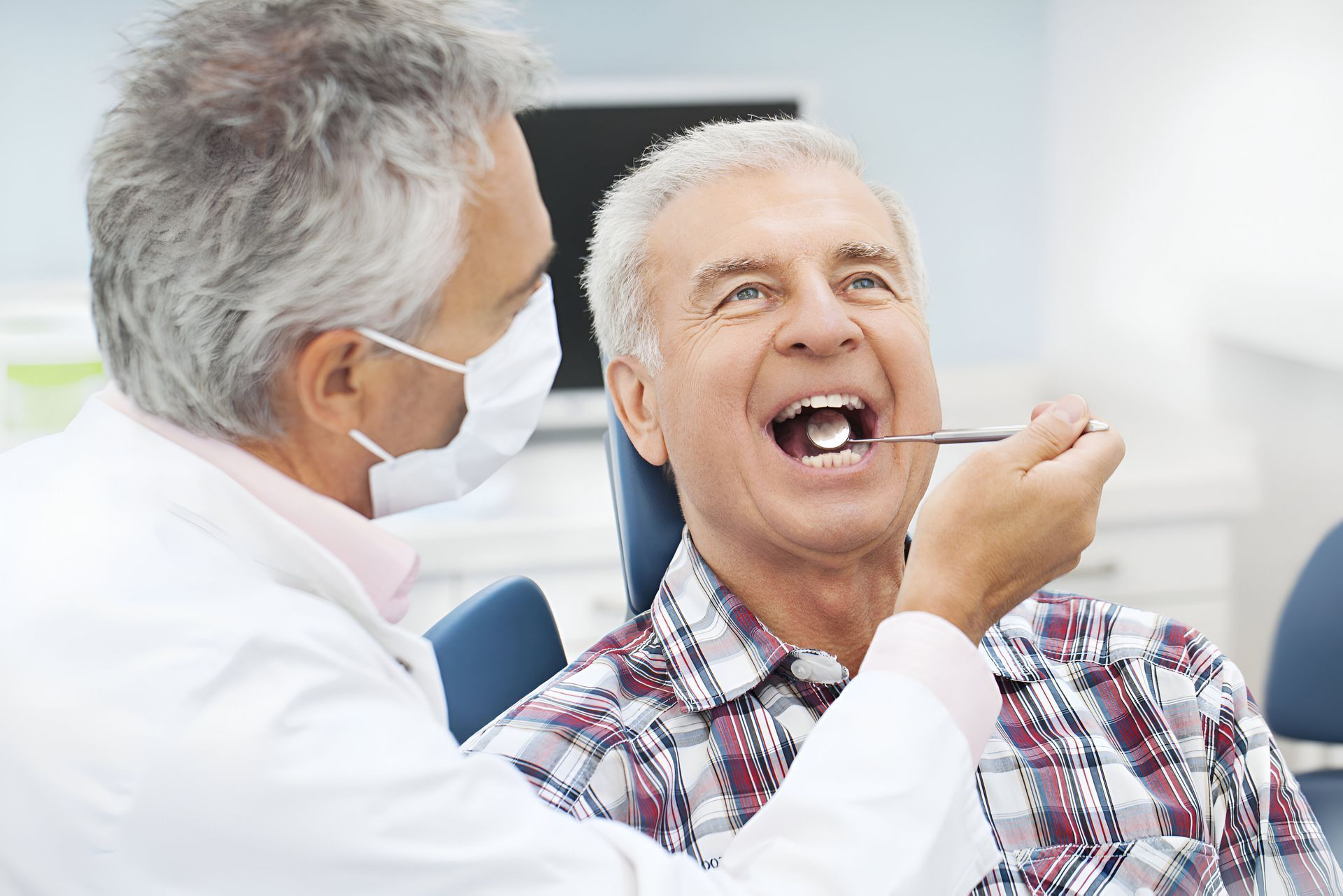 An older man is having his teeth examined by a dentist.