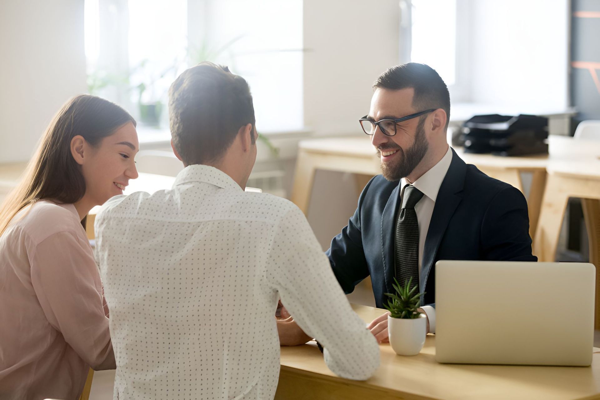 A Man In A Suit And Tie Is Sitting At A Table With A Woman And A Man — Grant Finance Solutions In Toowoomba, QLD